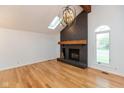 Bright living room features hardwood floors, a skylight, and a striking brick fireplace with a rustic wood beam at 12290 Charing Cross Rd, Carmel, IN 46033