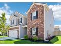 Modern two-story home with gray vinyl and red brick exterior complemented by green lawn and landscaping at 1452 Bigleaf Dr, Sheridan, IN 46069
