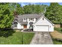 Charming two-story home with a well-manicured lawn, attached garage, and a welcoming, wooden front door at 14728 Adios Pass, Carmel, IN 46032