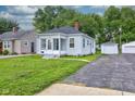 Inviting bungalow with a cozy front porch, landscaped lawn, and detached garage at 1517 Wallace Ave, Indianapolis, IN 46201