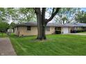 Charming single story home featuring a well-maintained yard with green grass, large tree, and one car garage at 3412 Loral Dr, Anderson, IN 46013
