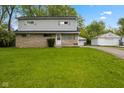 Charming two-story house with a large green lawn and a detached one-car garage in the background at 3425 N Elizabeth St, Indianapolis, IN 46226
