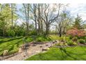 Serene backyard garden with stone walkway, mature trees, lush greenery, and decorative seating at 4281 Cairo Way, Avon, IN 46123