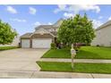 Attractive two-story home boasts a three car garage, stone details, green lawn, and a welcoming mailbox at 5593 Ralfe Rd, Indianapolis, IN 46234