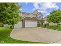 Lovely two-story home featuring stone accents, a three-car garage, a wide driveway, and green landscaping at 5593 Ralfe Rd, Indianapolis, IN 46234