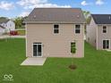 This home's backyard features a sliding glass door, small patio, and newly planted tree on a green lawn at 564 Plowman Dr, Shelbyville, IN 46176