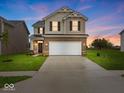Charming two-story home at dusk featuring brick and siding, complemented by a spacious two-car garage and manicured lawn at 564 Plowman Dr, Shelbyville, IN 46176