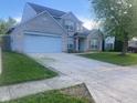 Two-story home with brick facade, large driveway, and well-maintained lawn at 6625 Wolverine Way, Indianapolis, IN 46237