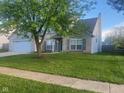 Charming home with large green tree, well-manicured lawn, and two car garage at 6625 Wolverine Way, Indianapolis, IN 46237