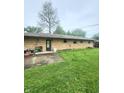 View of brick home's back exterior with a compact patio area and spacious backyard at 7109 Chandler Dr, Indianapolis, IN 46217