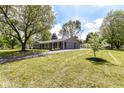 Ranch home featuring mature trees, a long driveway, and an attached garage at 7118 Mikesell Dr, Indianapolis, IN 46260