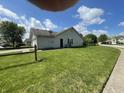 A large, well-manicured side yard with lush green grass surrounds the house and a partial fence at 8234 Crosser Dr, Indianapolis, IN 46237