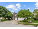 Traditional brick and siding home with a large front yard and a two-car garage, landscaped with mature trees at 8316 Thorn Bend Dr, Indianapolis, IN 46278