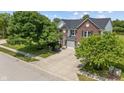 Classic brick home with lush landscaping, a large driveway, and an attached two-car garage on a sunny day at 8316 Thorn Bend Dr, Indianapolis, IN 46278