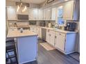 Updated kitchen featuring white cabinetry, dark wood-look floors, stainless appliances, and a cozy center island at 8798 Surrey Dr, Pendleton, IN 46064