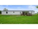 A single-story home with white siding and a covered wooden deck in a grassy yard at 9621 N County Road 25 W, Muncie, IN 47303