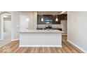 Bright kitchen featuring a center island with sink, granite countertops, and dark cabinetry at 10307 Gateway Dr, Brownsburg, IN 46234
