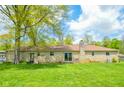 Expansive backyard featuring a stone home with a brick chimney and sliding glass doors at 10827 Wonderland Dr, Indianapolis, IN 46239