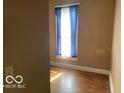 Small bedroom with hardwood flooring, a window with blue curtains, and neutral paint on the walls at 1440 E Morgan E St, Martinsville, IN 46151