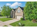 Attractive brick home featuring a well-kept lawn, mature trees, and a spacious two-car garage at 1454 Woodfield Dr, Greenwood, IN 46143