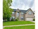 Charming two-story brick home with a green lawn, a two-car garage, and a beautifully landscaped front yard at 1454 Woodfield Dr, Greenwood, IN 46143
