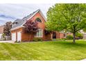 Two-story brick home featuring manicured lawn, mature trees, and attached garage at 1510 Continental Dr, Zionsville, IN 46077
