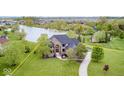 An aerial view of the beautiful brick home with water view and stunning landscaping at 16285 Remington Dr, Fishers, IN 46037