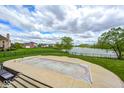 Backyard view of the pool, fence, lawn and lake view at 16285 Remington Dr, Fishers, IN 46037