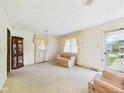 Spacious living room featuring neutral carpet, large windows, comfortable seating, and a glass display cabinet at 209 E 35Th St, Anderson, IN 46013