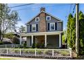 Charming two-story home featuring gray siding, brick chimney, a front porch, and a neatly manicured yard at 413 E 40Th St, Indianapolis, IN 46205