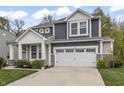 Traditional home features a two-car garage, blue and gray siding, a manicured lawn, and a classic design at 4629 Rainwater Ln, Whitestown, IN 46075