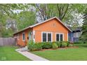 Charming orange single-story home featuring a well-manicured lawn and a vibrant blue door at 4810 Winthrop Ave, Indianapolis, IN 46205