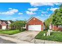 Brick home featuring a well-manicured lawn and a two-car garage with a concrete driveway at 5348 Pelham Way, Indianapolis, IN 46216