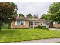 Beautiful brick home featuring a large lawn, mature trees, and an attached two-car garage with basketball hoop at 8103 Rumford Rd, Indianapolis, IN 46219