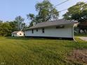 A single-story home shows its vinyl siding, contrasted by lush green grass and a detached garage at 1009 Chestnut St, Anderson, IN 46012