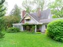 Quaint two-story home with lush greenery and a charming yellow awning at 1207 Van Buskirk Rd, Anderson, IN 46011