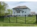 Backyard view featuring a deck, expansive lawn, and wrought iron fence at 12811 Corydon Dr, Fishers, IN 46037