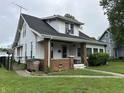 Traditional home with dark roof, covered porch, small yard, and chain link fence at 1618 California St, Columbus, IN 47201