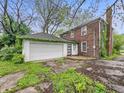 A two-car detached garage in a backyard with greenery and trees, connected to the two-story home at 3516 Janet Dr, Indianapolis, IN 46218