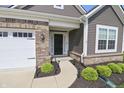 Close up of front entrance featuring a black door, brick accents, and manicured shrubs at 4324 Homestead Dr, Whitestown, IN 46075