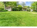 Ranch-style home featuring an attached garage and a spacious front yard with lush green grass and mature trees at 5648 Rolling Ridge Rd, Indianapolis, IN 46220