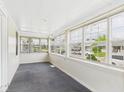 Bright sunroom featuring white wood paneling, gray carpet, and multiple windows with neighborhood views at 717 E 27Th St, Anderson, IN 46016