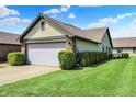 Spacious front yard with a two-car garage and lush green landscaping, creating a welcoming outdoor space at 7702 Justin Ln, Indianapolis, IN 46219