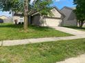 Well maintained brick house with green lawn and mature tree in the front yard at 8054 Painted Pony Dr, Indianapolis, IN 46217