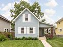 Charming two-story home with light blue siding and a lush green lawn, complemented by mature trees at 809 N Temple Ave, Indianapolis, IN 46201