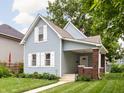 Charming light blue two-story home features a well-maintained lawn and inviting front porch with brick supports at 809 N Temple Ave, Indianapolis, IN 46201