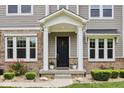 Close up of the covered front porch featuring stone pillars and decorative plants at 9155 Kerwood Dr, Indianapolis, IN 46240