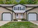 Inviting townhome featuring a two-car garage, neutral siding, green trim, and a well-maintained lawn at 9493 Timber View Dr, Indianapolis, IN 46250