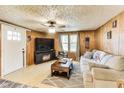 Cozy living room with wood paneled walls, a ceiling fan, comfortable sofa, and a TV with a fireplace at 115 S Center St, Maxwell, IN 46154