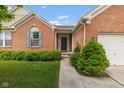 Inviting brick home featuring a covered entryway, manicured bushes, and a well-kept lawn at 14018 Powder Dr, Carmel, IN 46033
